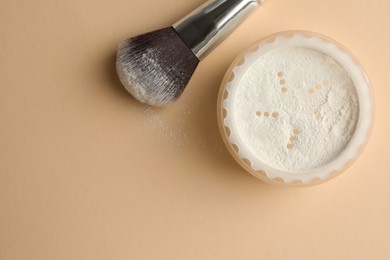 Photo of Rice loose face powder and makeup brush on beige background, flat lay. Space for text