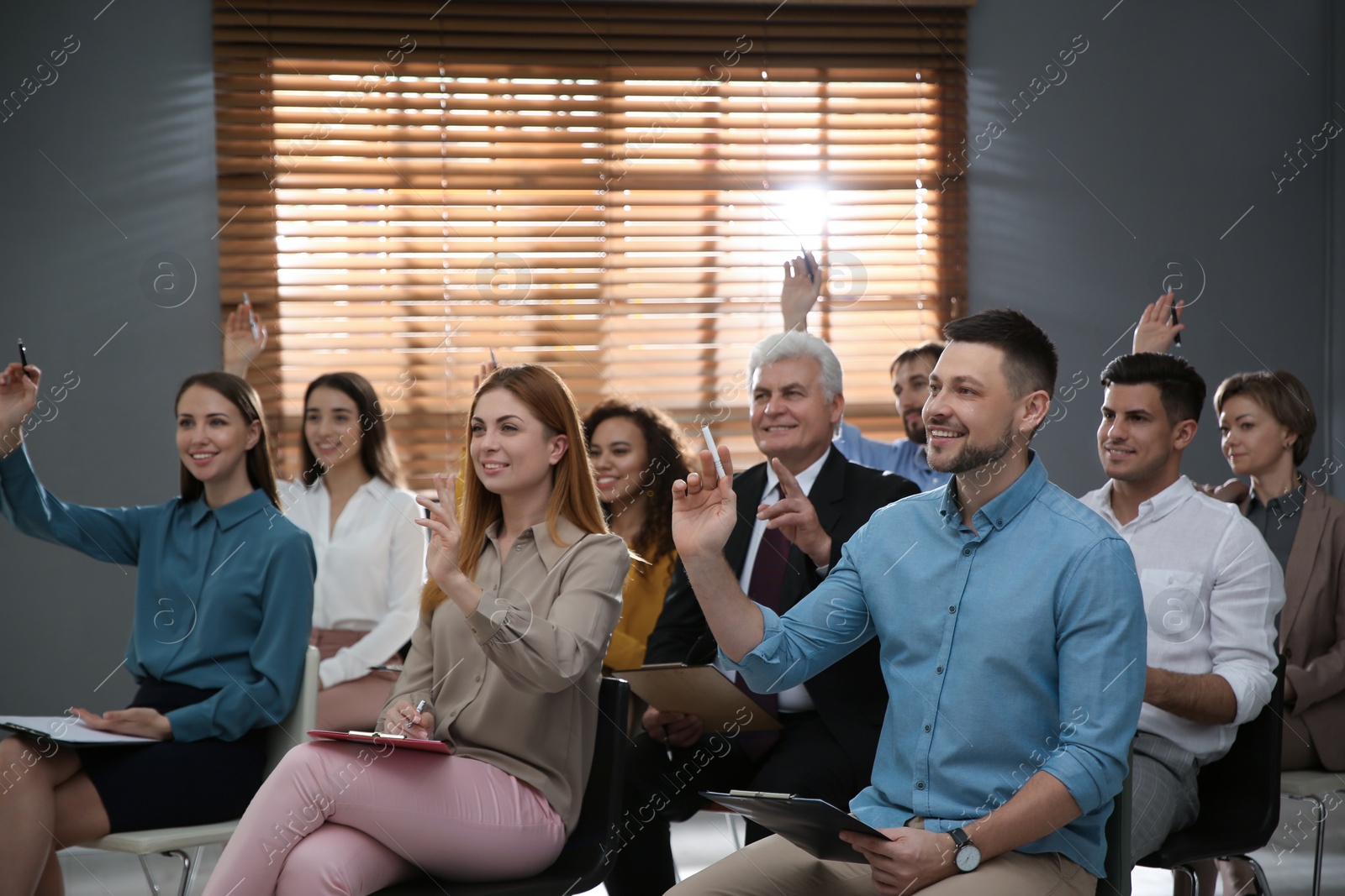 Photo of People raising hands to ask questions at seminar in office