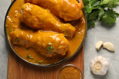 Tasty chicken curry and ingredients on grey textured table, flat lay