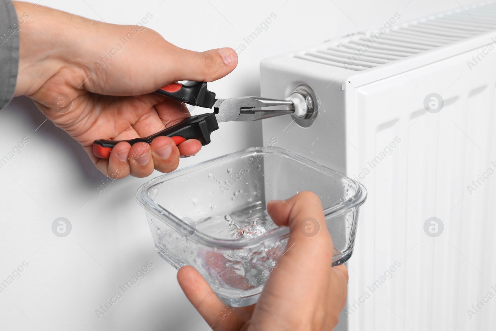 Photo of Man using pliers while preparing heating radiator for winter season, closeup