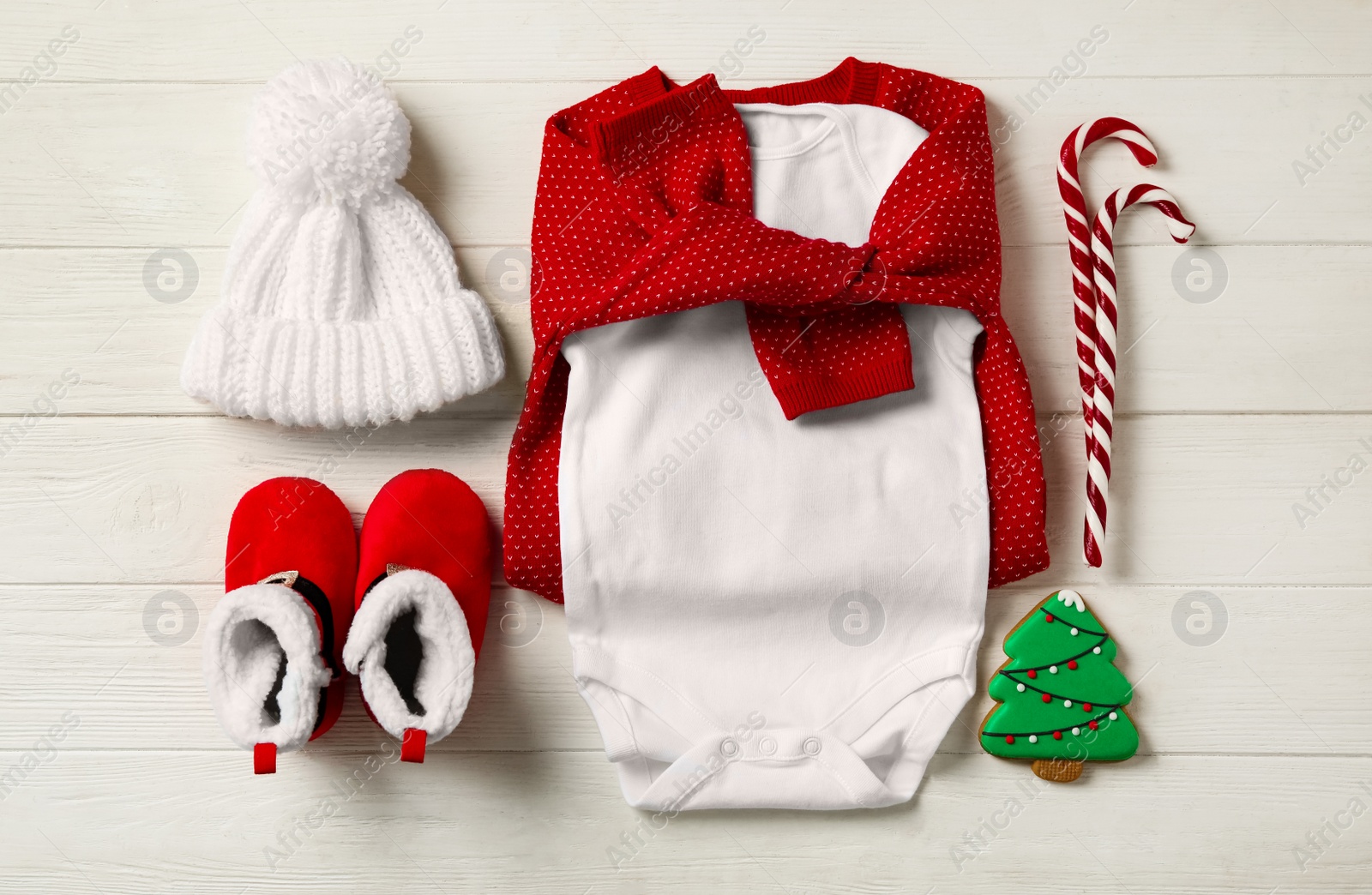 Photo of Flat lay composition with cute Christmas baby clothes on white wooden background