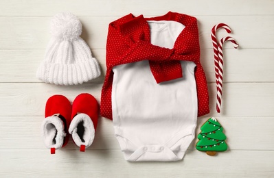 Flat lay composition with cute Christmas baby clothes on white wooden background