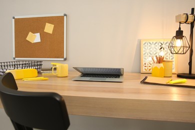 Stylish workplace with laptop on wooden desk near light wall. Interior design