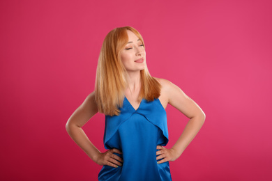 Beautiful young woman with blonde hair on pink background