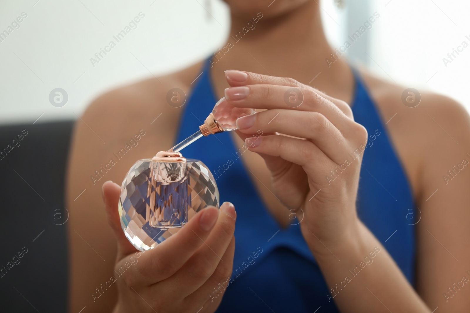 Photo of Young woman with bottle of perfume indoors, closeup