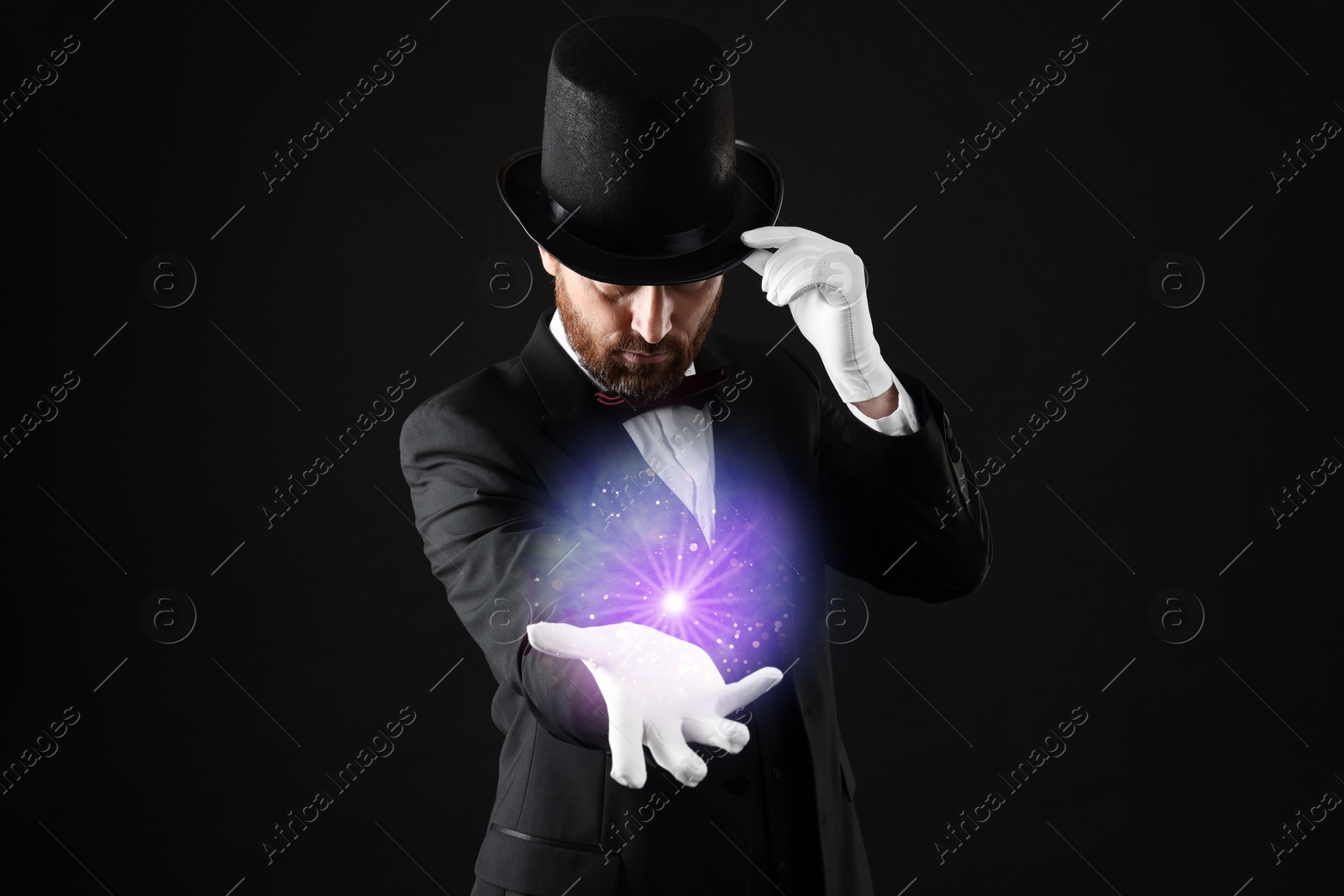 Image of Magic and sorcery. Magician with fantastic light on dark background