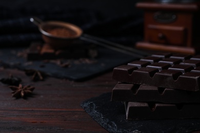 Photo of Tasty dark chocolate bars on wooden table, closeup