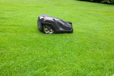Photo of Modern lawn mower on green grass outdoors