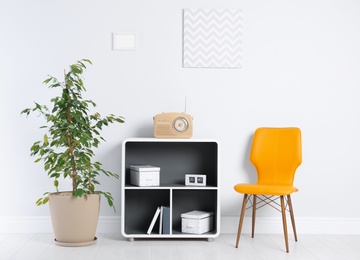 Photo of Stylish living room interior with chair and houseplant near white wall