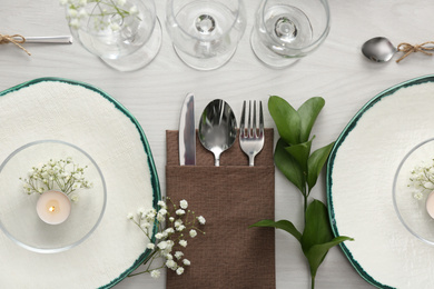 Elegant table setting with green plants on white wooden background, flat lay