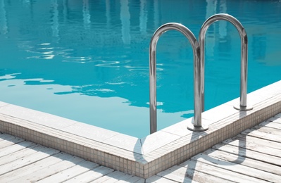 Modern swimming pool with ladder at resort