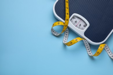 Photo of Scales and measuring tape on light blue background, flat lay. Space for text