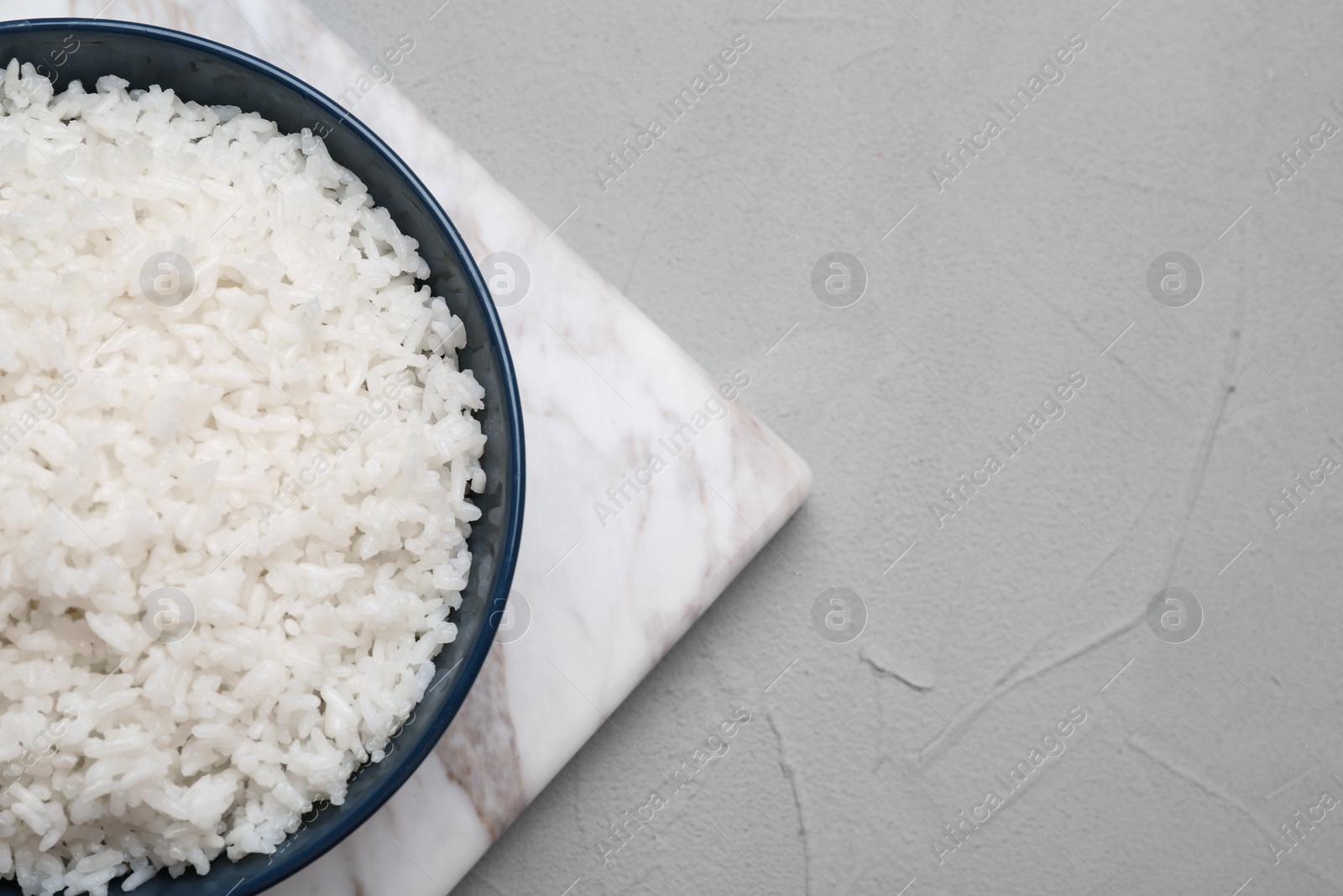 Photo of Bowl of boiled rice on color background, top view with space for text