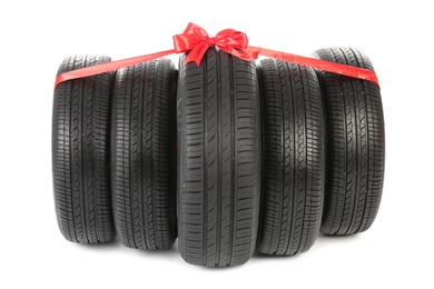 Car tires tied with red ribbon on white background