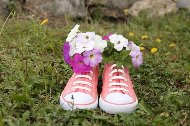 Shoes with beautiful flowers on grass outdoors