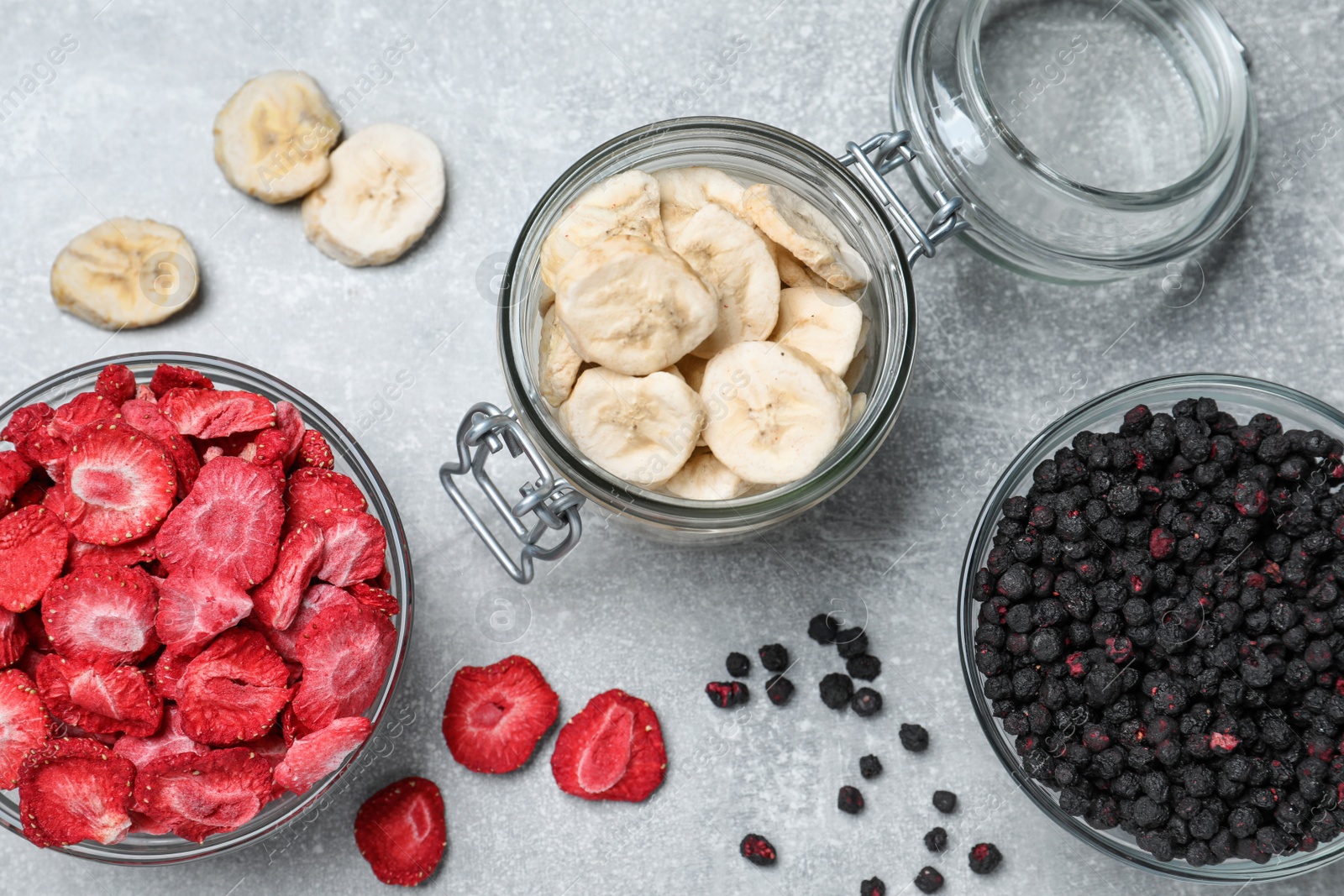 Photo of Many different freeze dried fruits on light grey table, flat lay