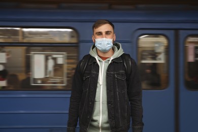 Young man in protective mask near subway train. Public transport