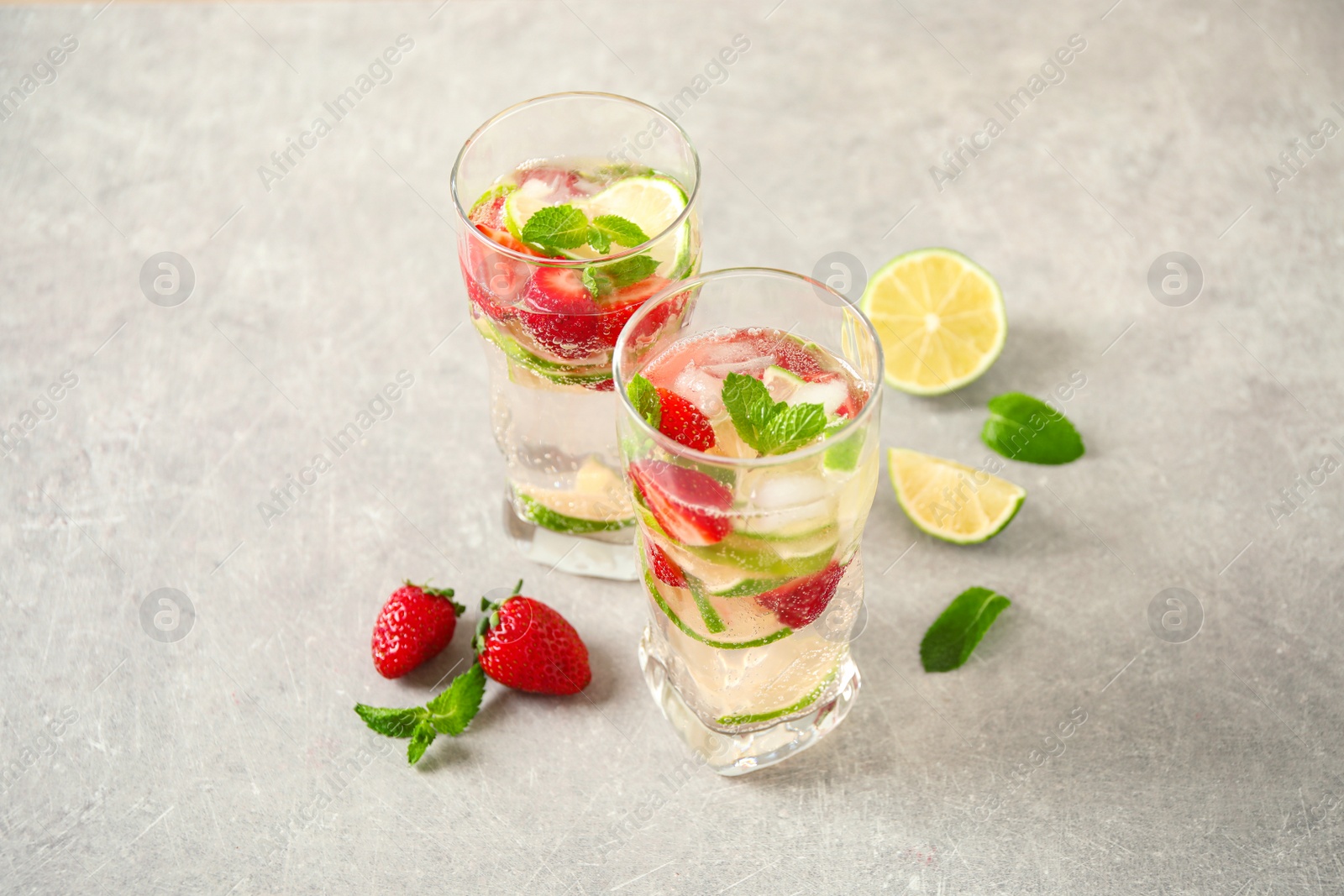 Photo of Tasty refreshing drink with strawberry on light grey table