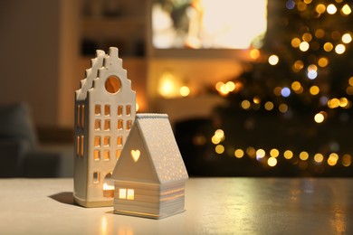 Beautiful house shaped candle holders on table indoors, space for text. Bokeh effect
