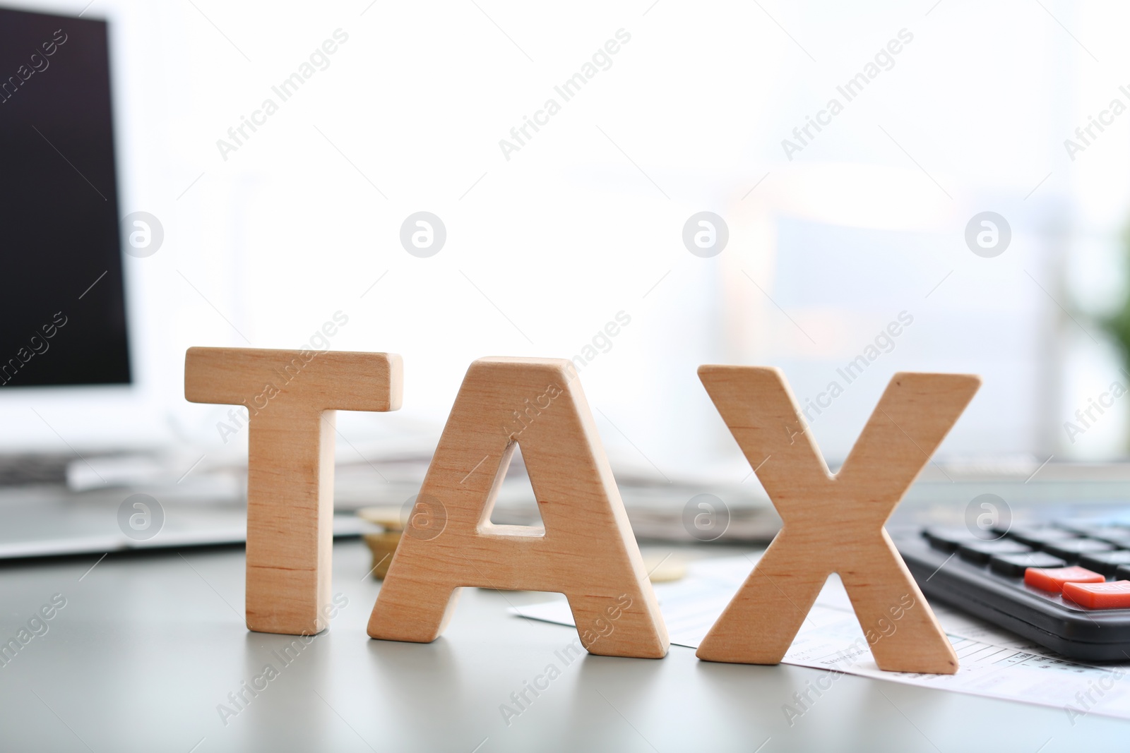 Photo of Word TAX on table against blurred background