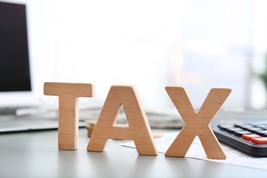 Photo of Word TAX on table against blurred background
