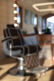 Photo of Blurred view of stylish hairdresser's workplace with professional armchair in barbershop