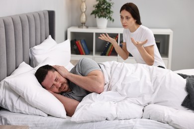 Photo of Stressed husband ignoring his wife in bed, selective focus. Relationship problems
