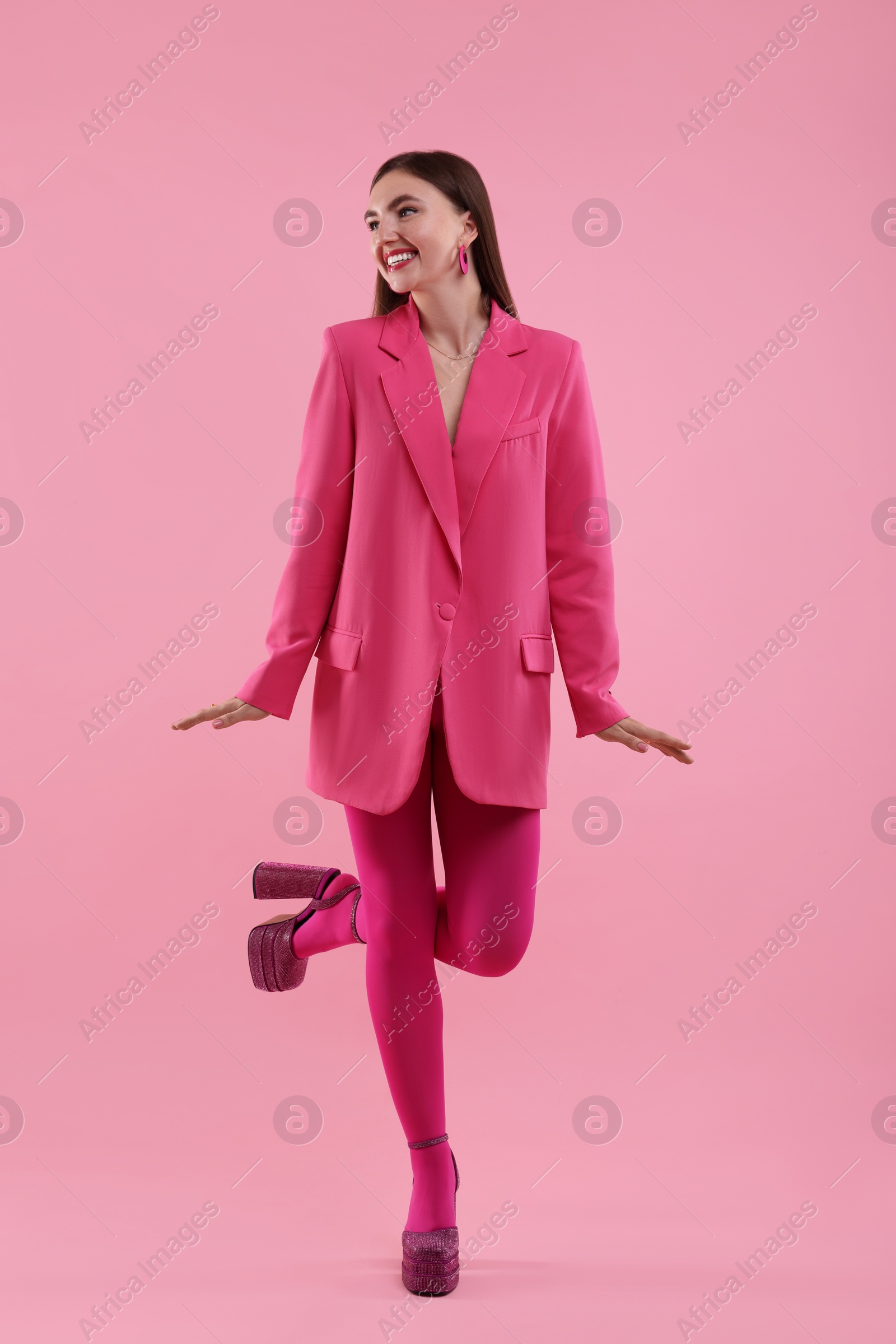 Photo of Beautiful young woman in pink clothes on color background