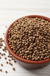 Photo of Dried coriander seeds in bowl on wooden table, closeup