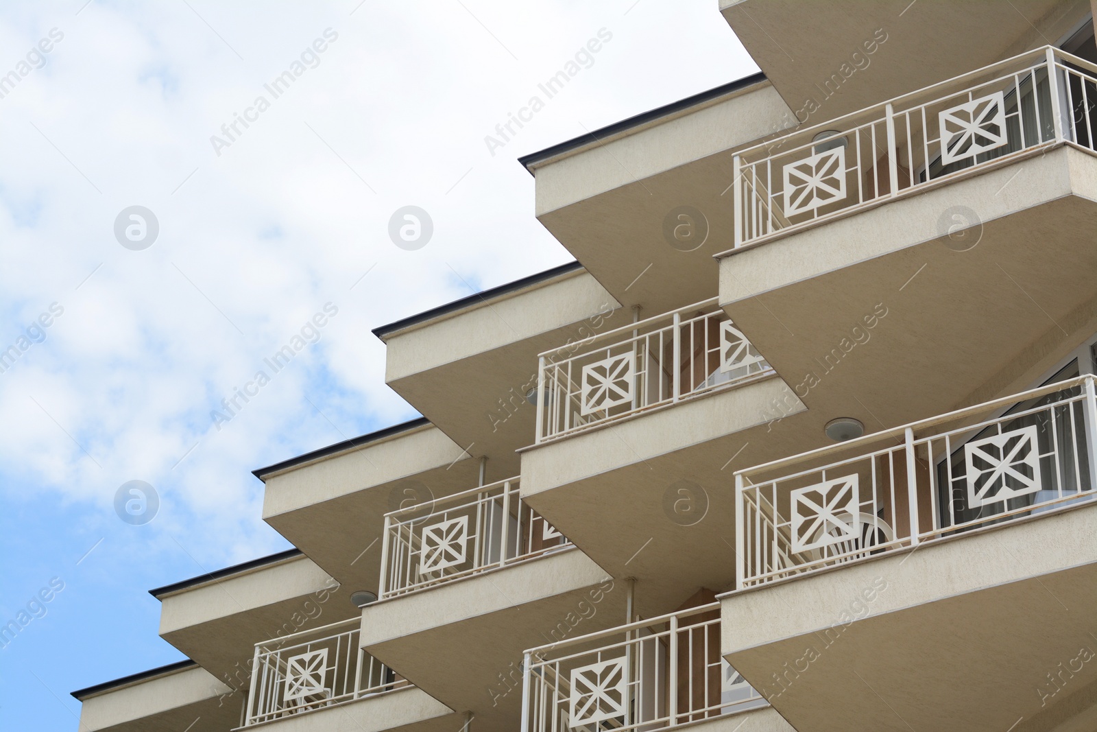 Photo of Exterior of beautiful building with balconies against blue sky, low angle view