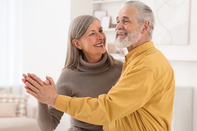 Photo of Affectionate senior couple dancing in living room at home