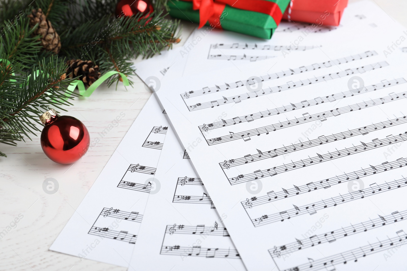 Photo of Composition with Christmas music sheets with notes on white wooden background, closeup