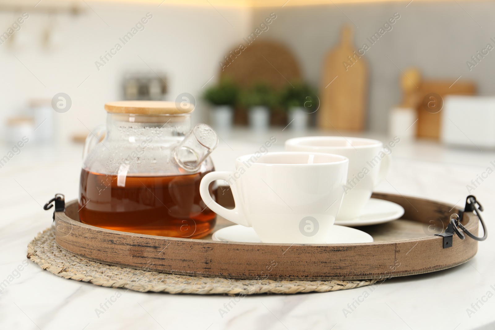 Photo of Aromatic tea in glass teapot and cups on white table