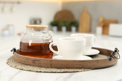 Aromatic tea in glass teapot and cups on white table