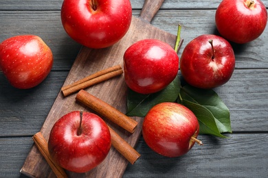 Fresh apples and cinnamon sticks on wooden table