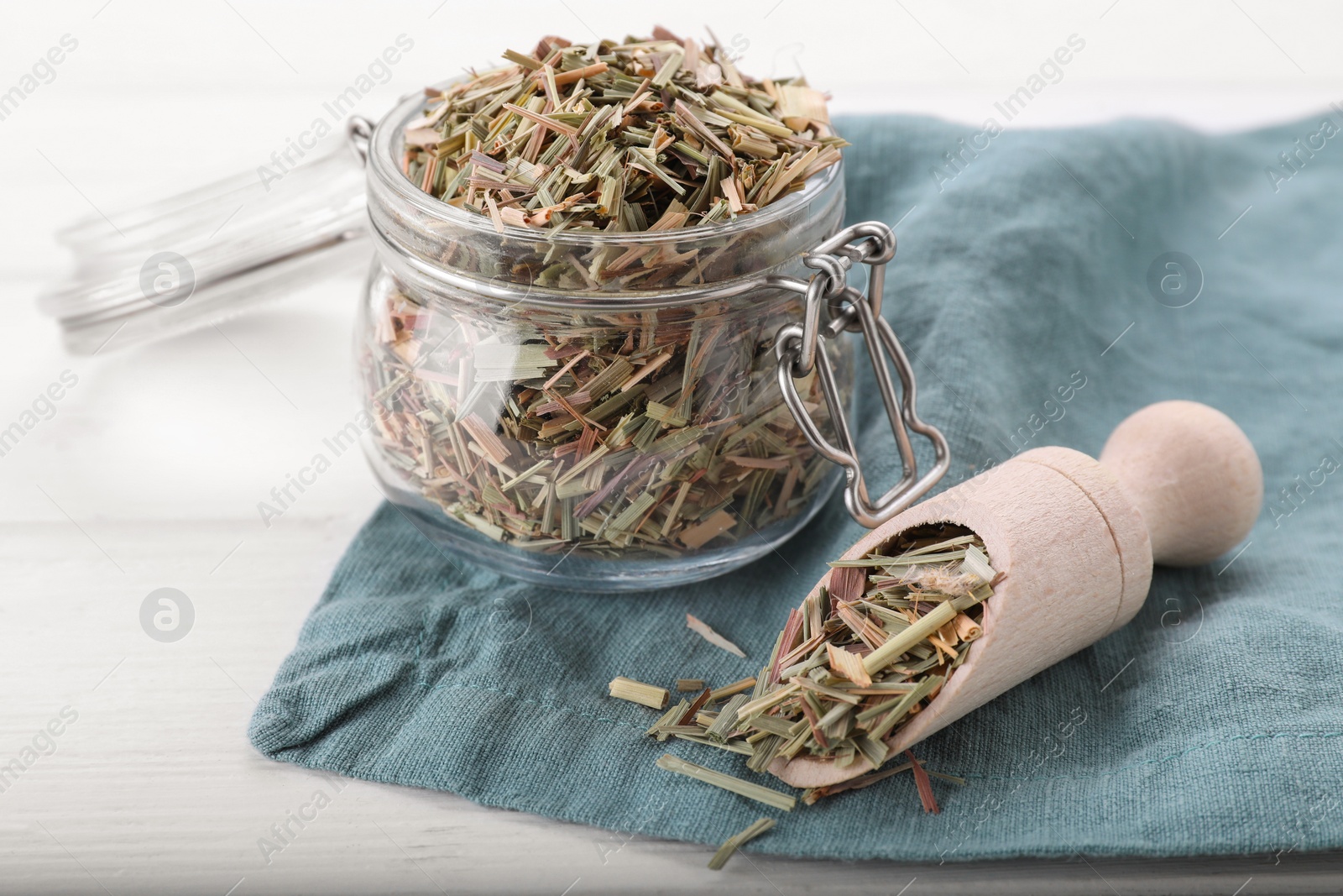 Photo of Jar and scoop with aromatic dried lemongrass on white table