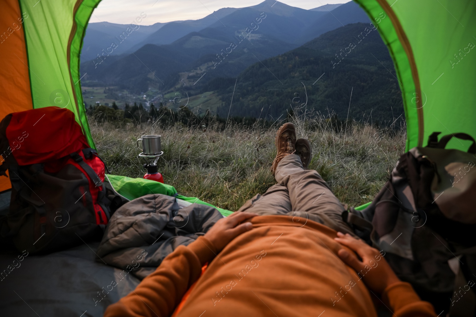 Photo of Man resting inside of camping tent in mountains, closeup