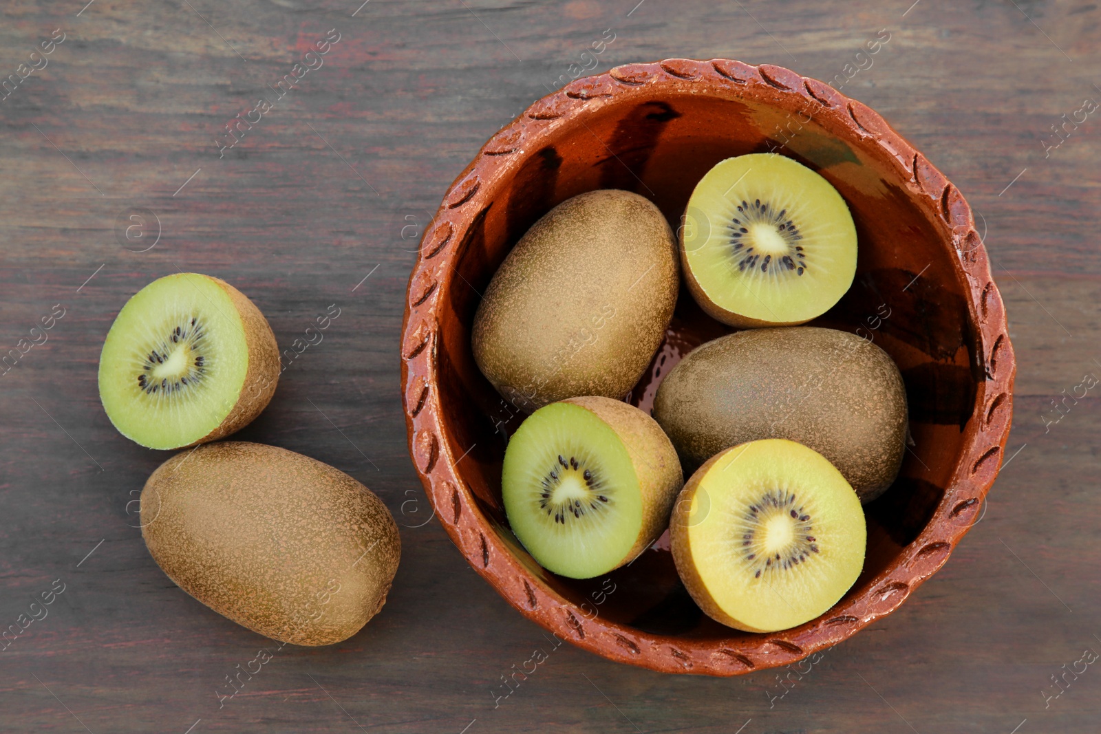 Photo of Whole and cut fresh kiwis on wooden table, flat lay