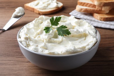 Photo of Tasty cream cheese with parsley on wooden table