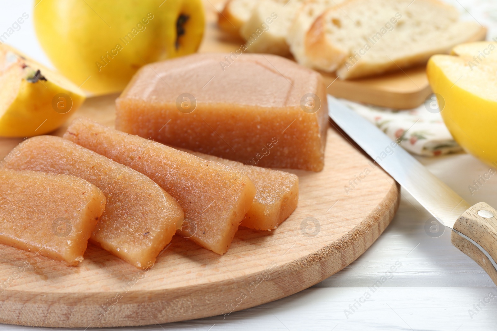 Photo of Tasty sweet quince paste, fresh fruits and knife on white wooden table, closeup