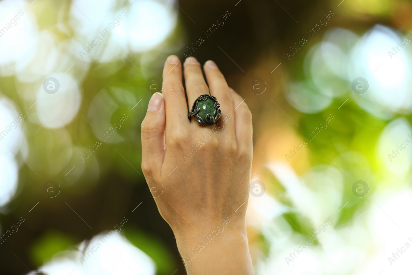 Photo of Young woman wearing beautiful silver ring with opal gemstone outdoors, closeup