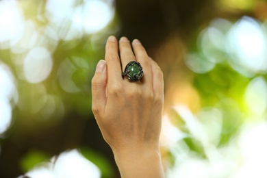 Photo of Young woman wearing beautiful silver ring with opal gemstone outdoors, closeup
