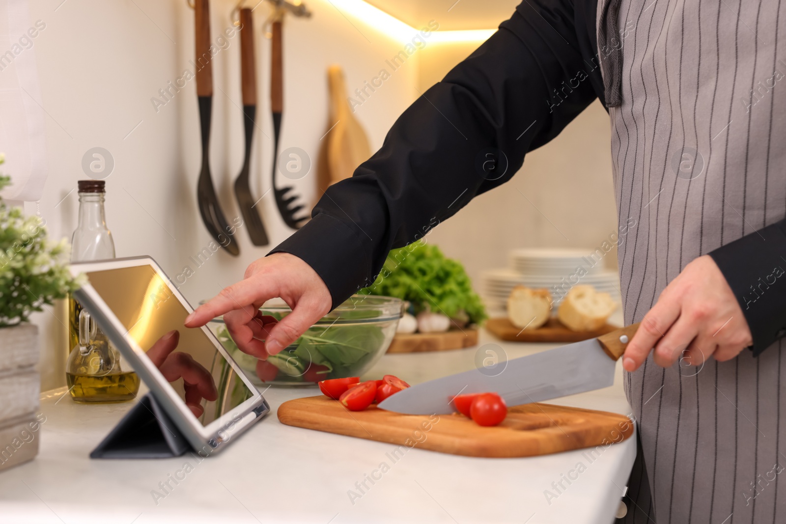 Photo of Man using tablet while cooking at countertop in kitchen, closeup