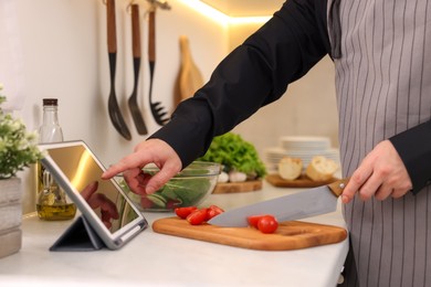 Photo of Man using tablet while cooking at countertop in kitchen, closeup