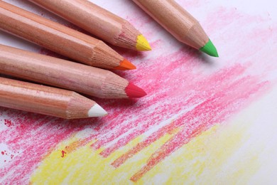 Photo of Colorful pastel pencils on abstract drawing, closeup