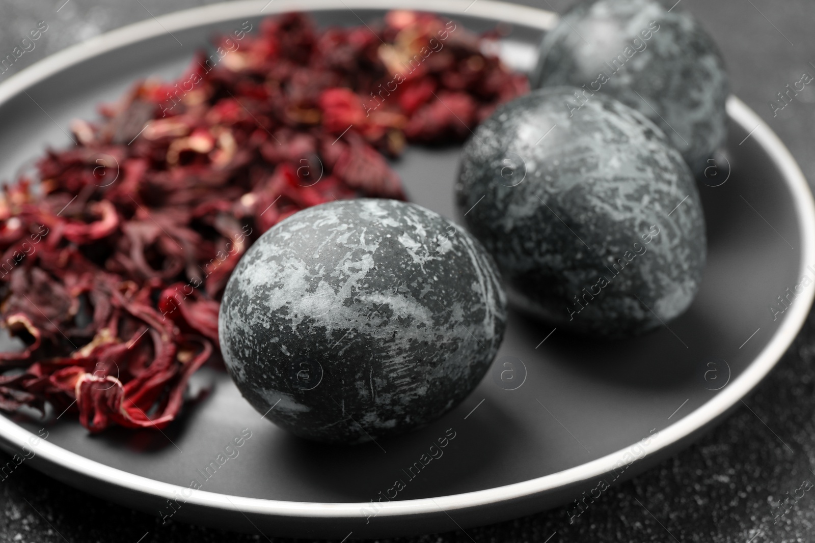 Photo of Naturally painted Easter eggs on black table, closeup. Hibiscus used for coloring