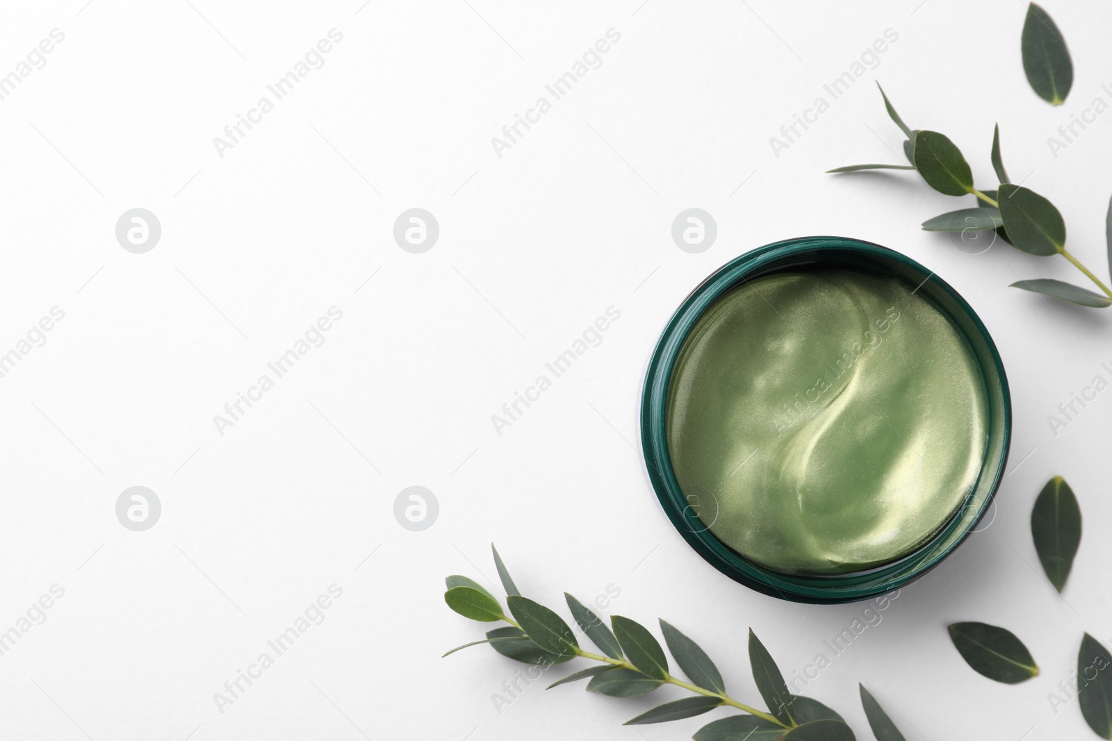Photo of Under eye patches in jar near green twigs on white background, flat lay. Space for text