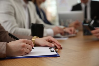 Photo of Woman writing at table during business meeting, closeup. Management consulting