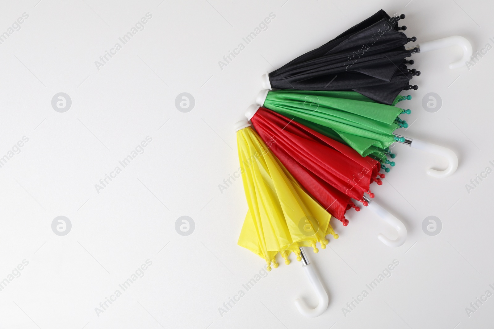 Photo of Small color umbrellas on white background, top view. Space for text