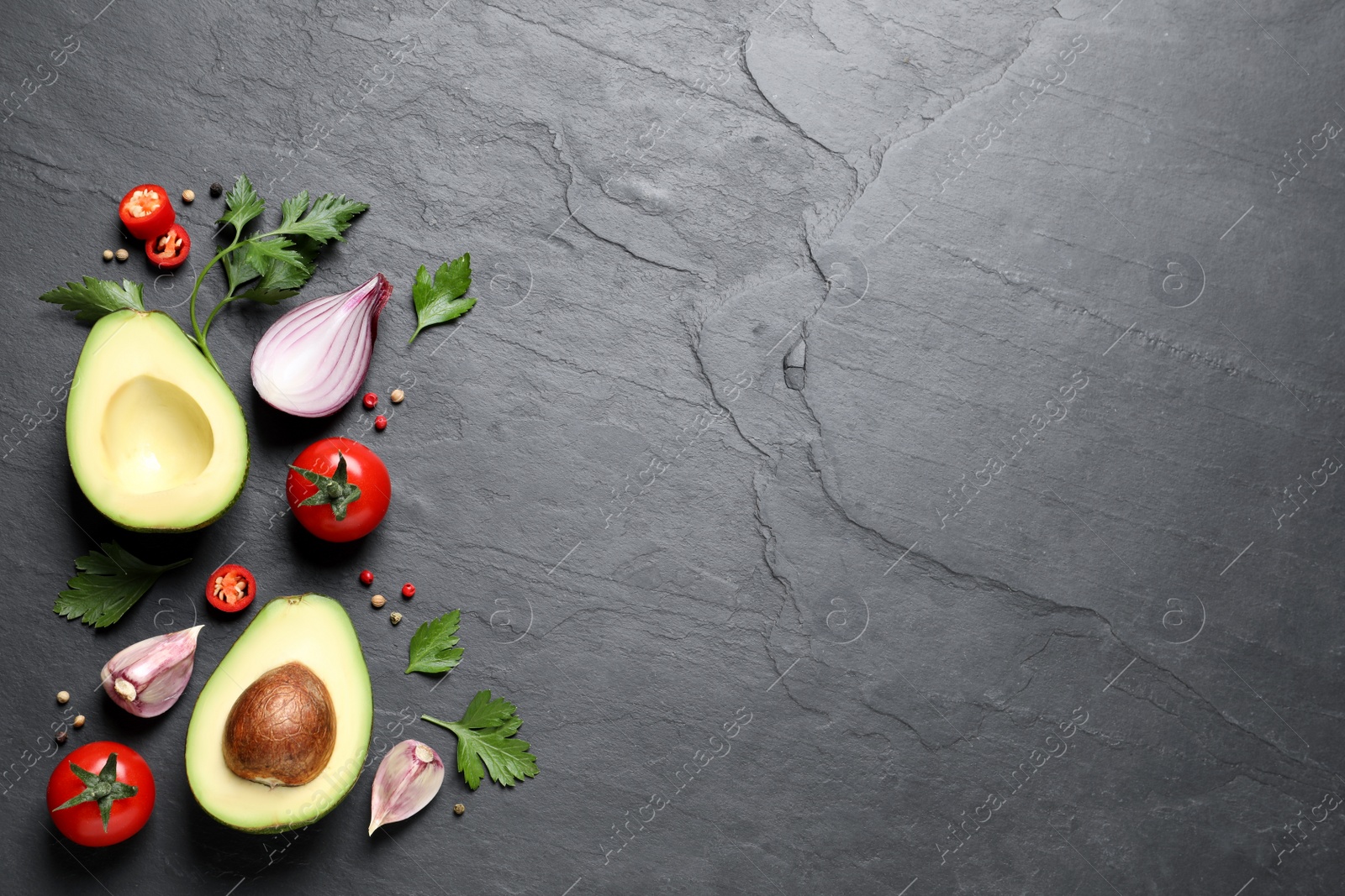 Photo of Fresh guacamole ingredients on black table, flat lay. Space for text